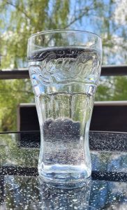 Ein mit Wasser gefülltes Cola-Glas